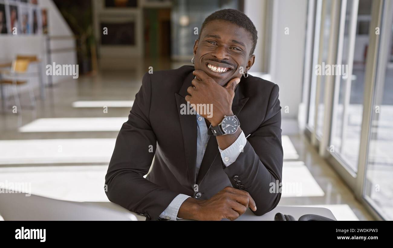 Ein lächelnder afroamerikaner in einem modernen Büro, das Selbstvertrauen und Professionalität ausstrahlt. Stockfoto