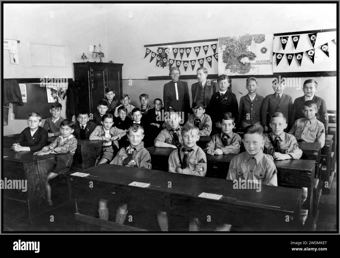 Nazi-Jugendschule der 1930er Jahre mit Hitler-Jugend Hitler-Jugend-Jungen in Uniorm im Klassenzimmer, mit Hakenkreuzfahnen dahinter, Radikalisierung in der Schulbildung 1930er Jahre Nazi-Deutschland Stockfoto