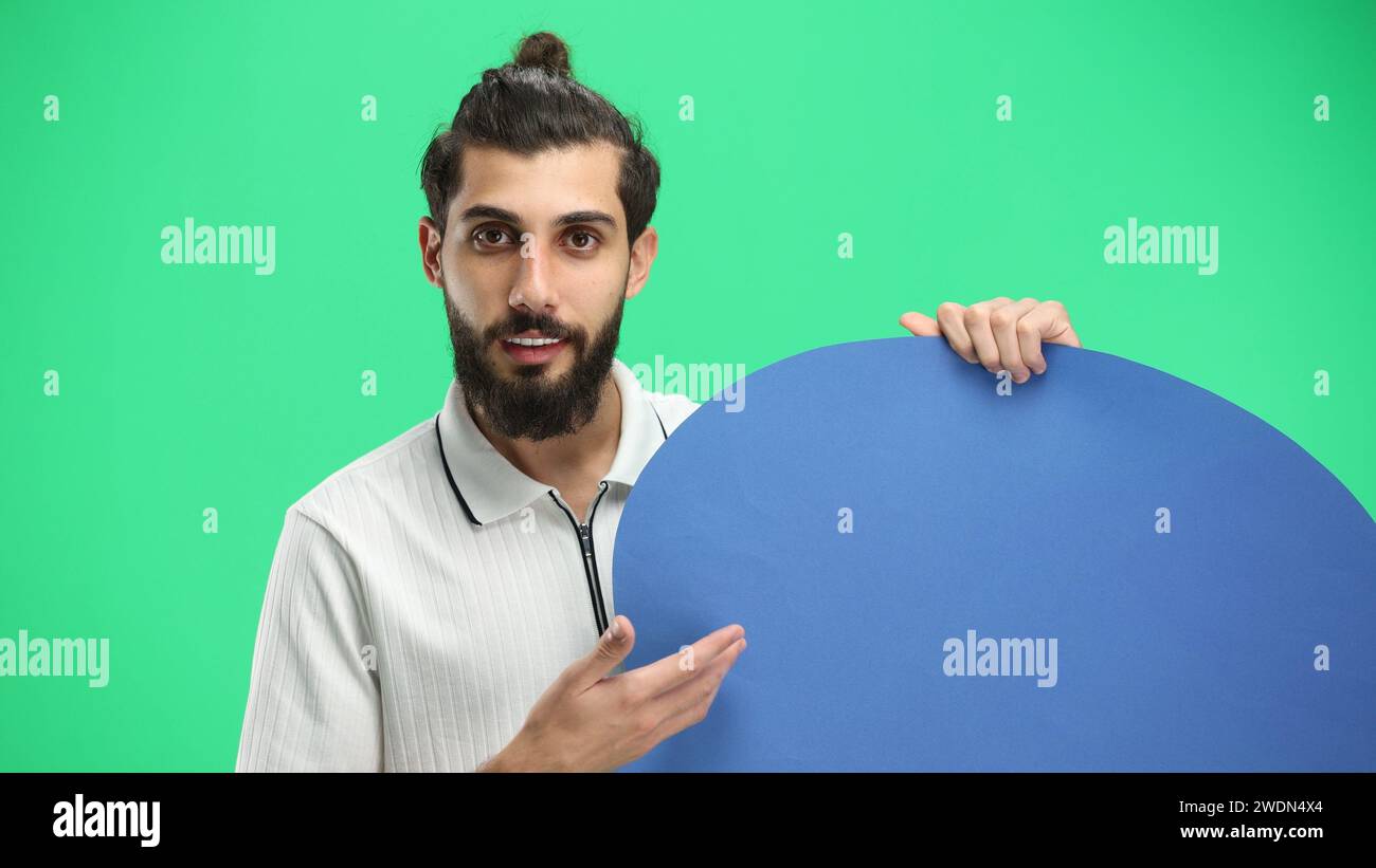 Ein Mann aus der Nähe auf grünem Hintergrund zeigt ein blaues Kommentarzeichen Stockfoto