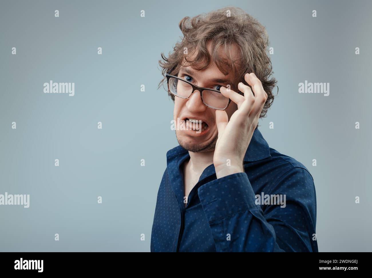 Mann mit Brillengrimaces, ein Anblick von Ekel, der sich als Reaktion auf eine unangenehme Situation manifestiert Stockfoto