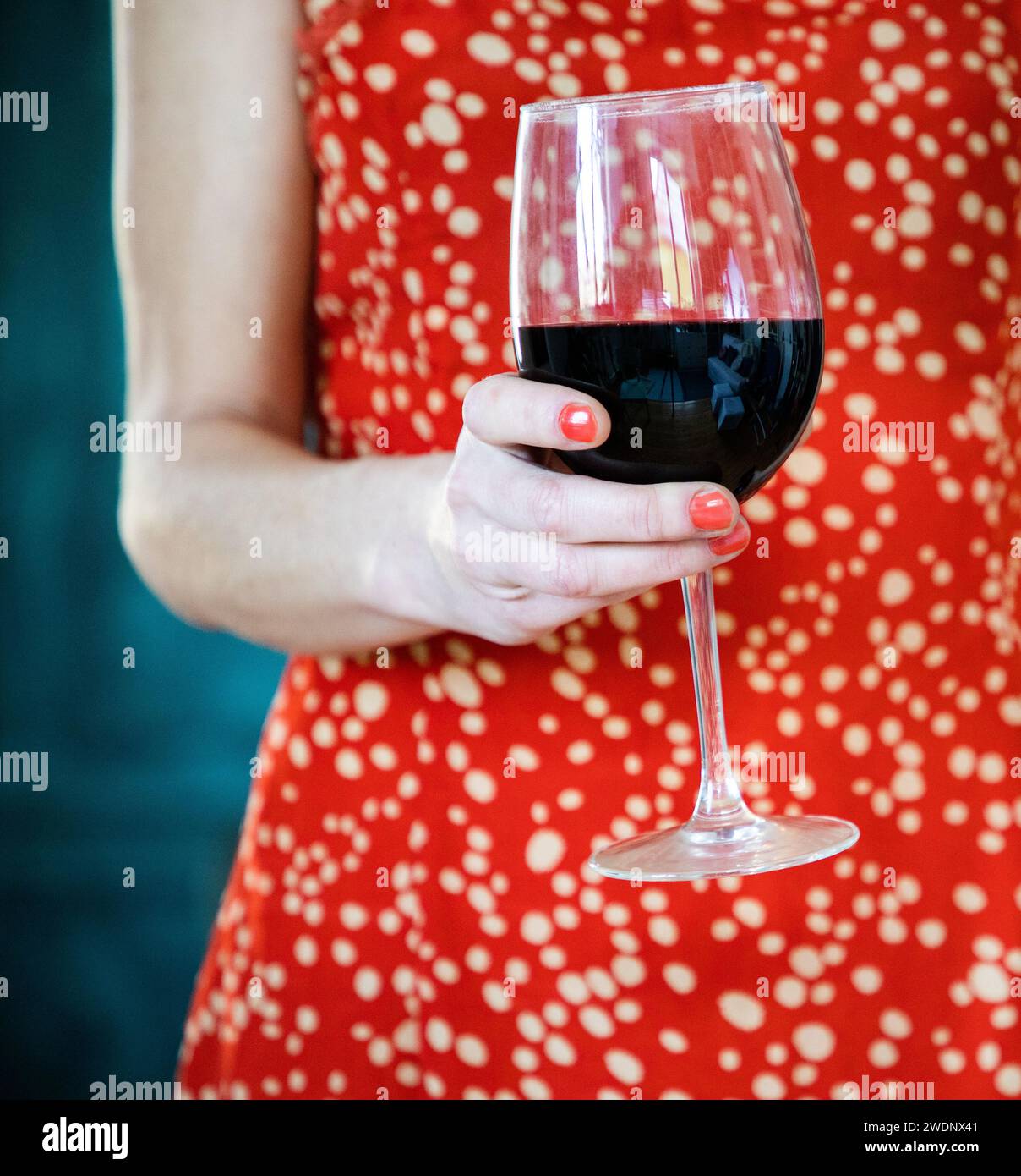 Frau in rotem Kleid, die Rotwein hält Stockfoto