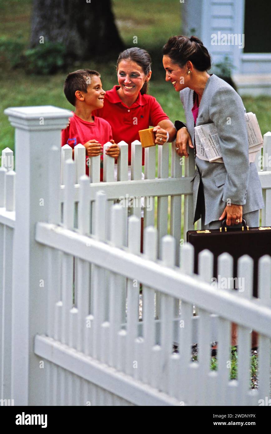 Eine Mutter und ein Sohn, die mit ihnen sprachen, waren ein neuer Nachbar auf der anderen Seite des Hinterhofzauns von White Pickett Stockfoto