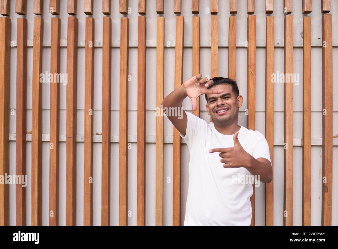 Junger Mann mit Zahnspangen, der mit Händen umrahmt Stockfoto
