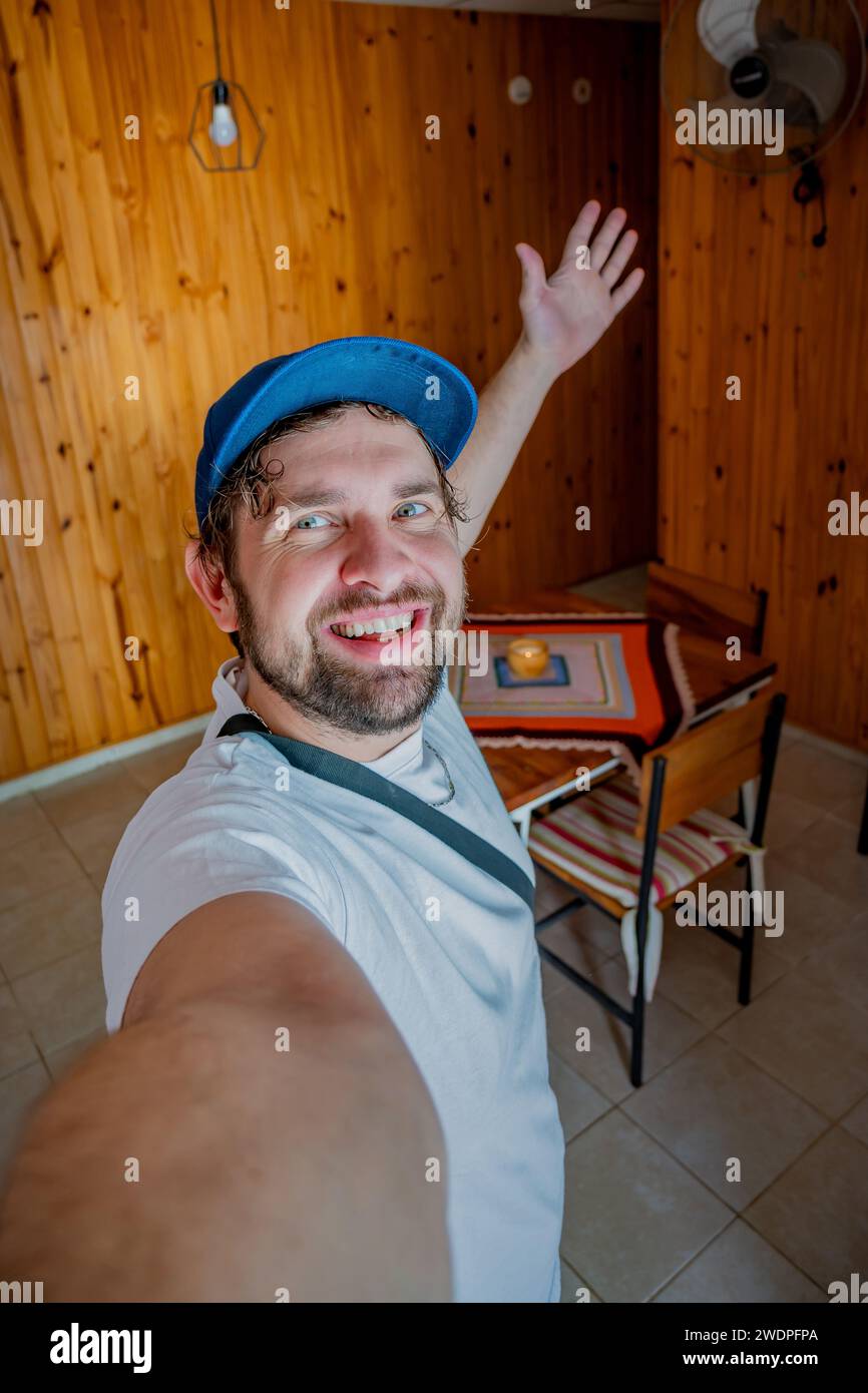 Ein junger Influencer freut sich, in seiner temporären Wohnung anzukommen und ein Selfie zu machen. Stockfoto