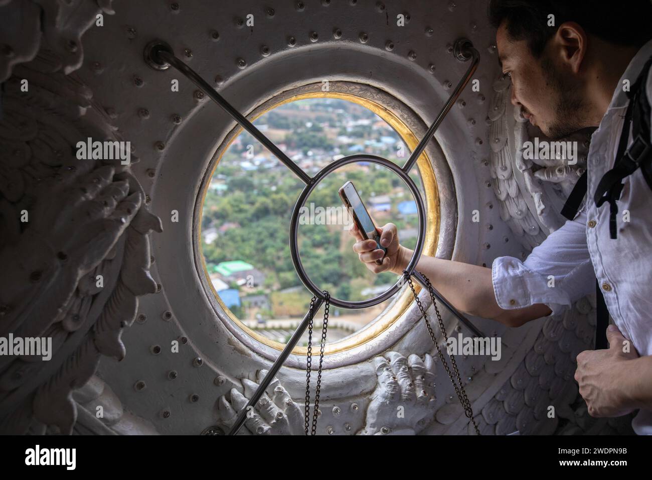 Chiang Rai, Thailand. Januar 2024. Ein Tourist macht ein Foto vom Fenster von Guanyin bindi aus der Guanyin-Statue. Der „Wat Huay Pla Kang“, auch bekannt als „großer Buddha von Chiang Rai“, ist bekannt für seine riesige weiße Statue von Guanyin (in der chinesischen Mythologie die Göttin der Barmherzigkeit). Der kürzlich erbaute Tempel ist eine Mischung aus thailändischem Lanna und chinesischem Stil und liegt auf einem Hügel im ländlichen Gebiet nördlich der Stadt Chiang Rai. (Credit Image: © Guillaume Payen/SOPA Images via ZUMA Press Wire) NUR REDAKTIONELLE VERWENDUNG! Nicht für kommerzielle ZWECKE! Stockfoto