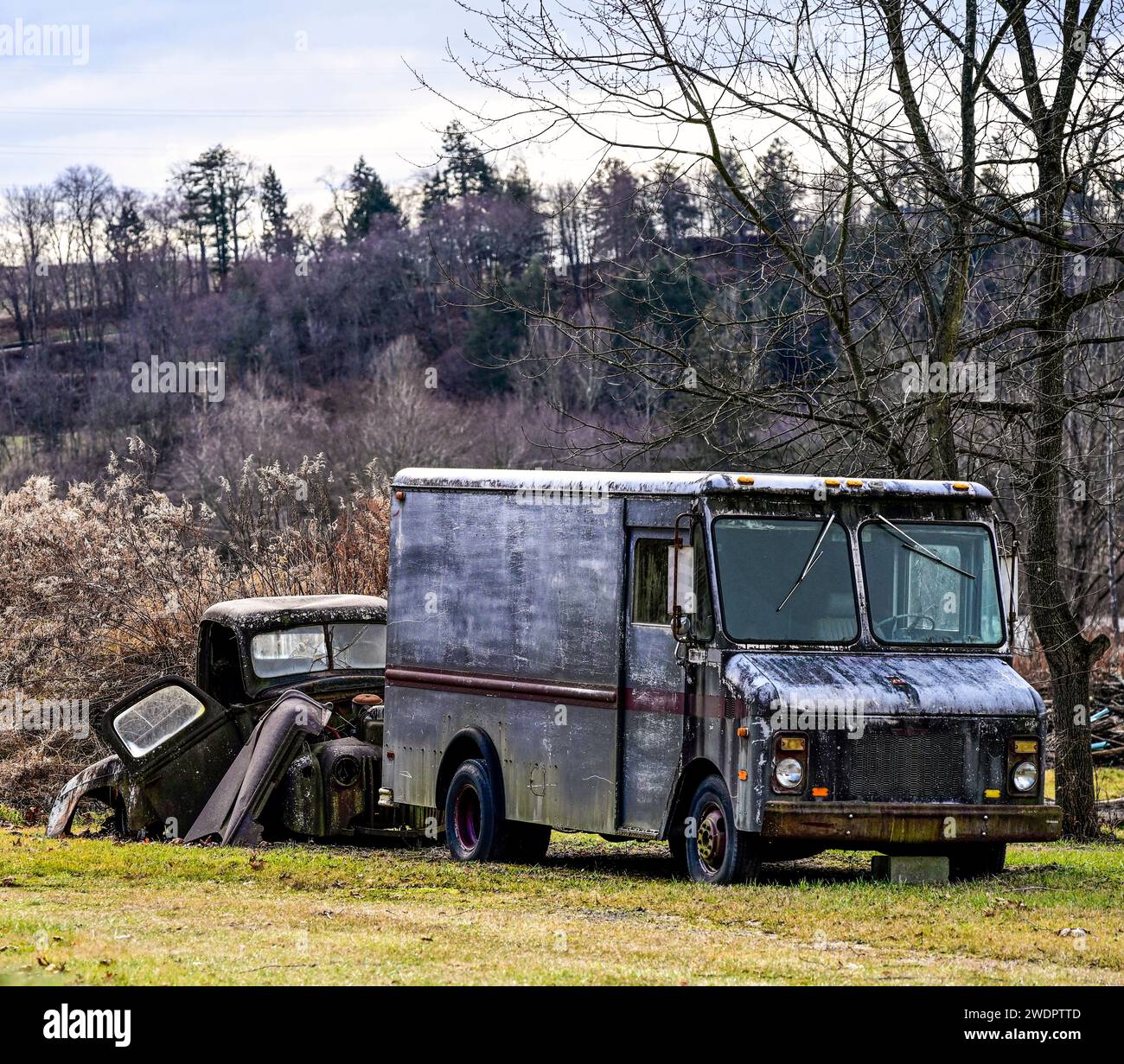 Ein verrosteter Truck, der auf dem Feld mit gestapelten alten Autos geparkt ist Stockfoto