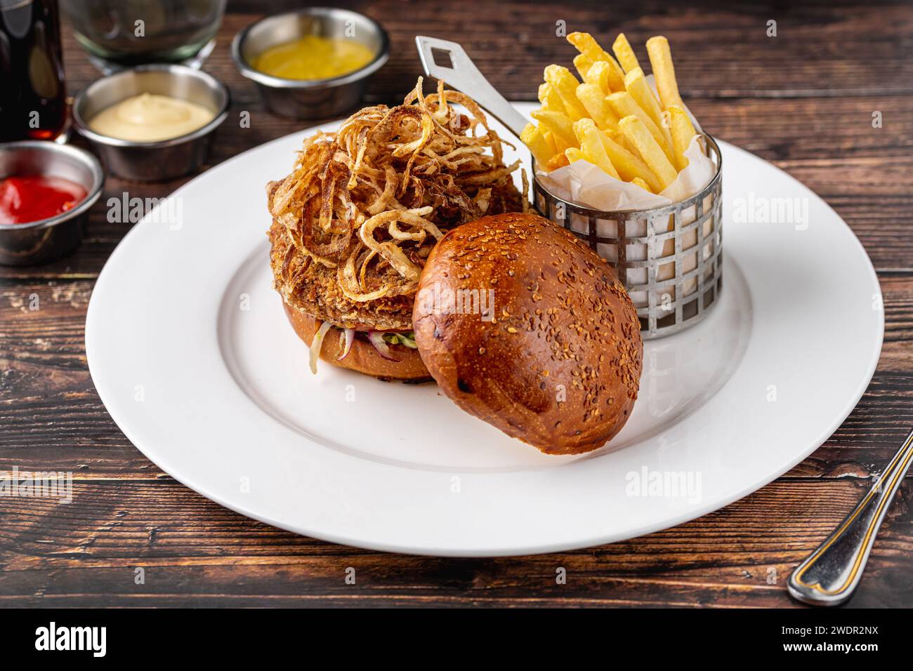 Veganer Burger mit knusprigen Zwiebeln, Saucen und Pommes Frites Stockfoto