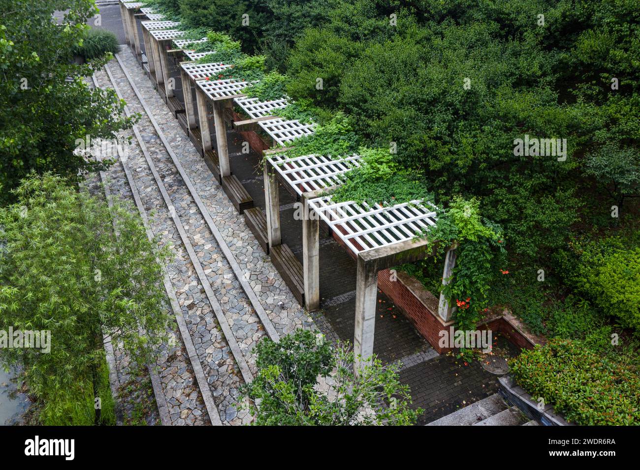 Ein Steinkorridor mit Treppen, umgeben von grünen Bäumen Stockfoto