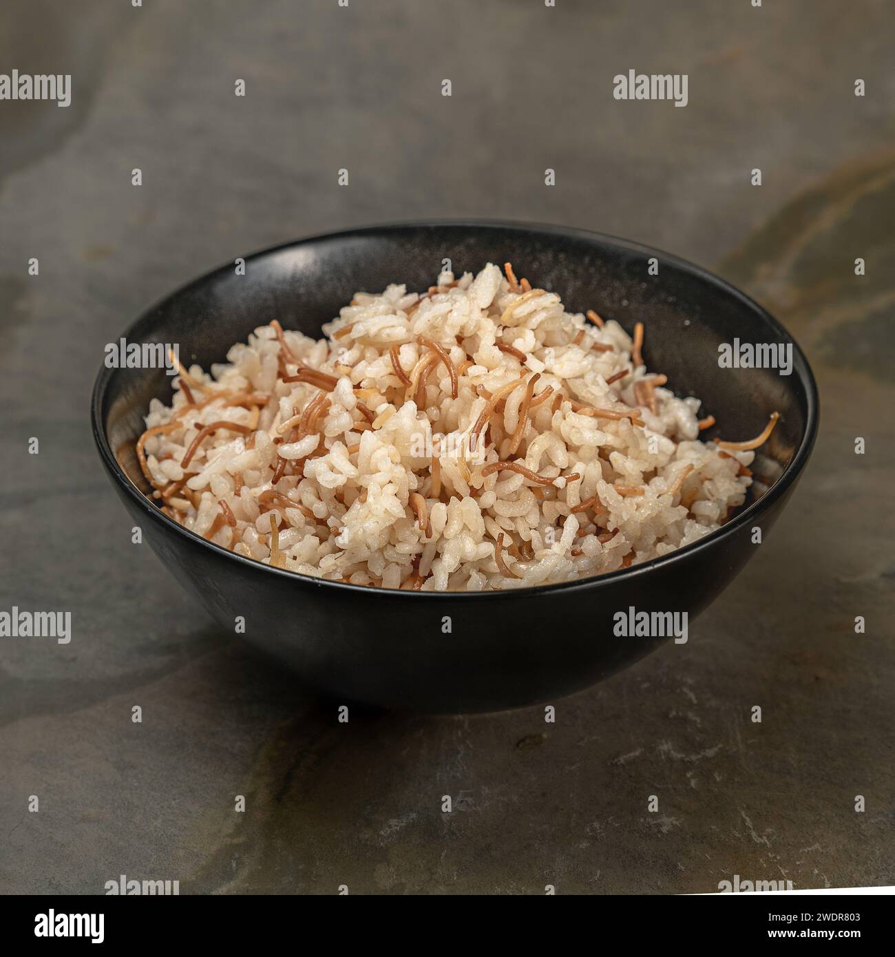 Eine Nahaufnahme mit Reis mit kleinen, türkischen Nudeln, die in einer schwarzen Schüssel serviert werden. Stockfoto