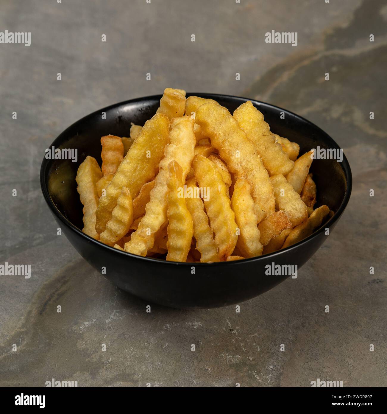 Eine Nahaufnahme von Pommes frites in einer schwarzen Schüssel. Stockfoto
