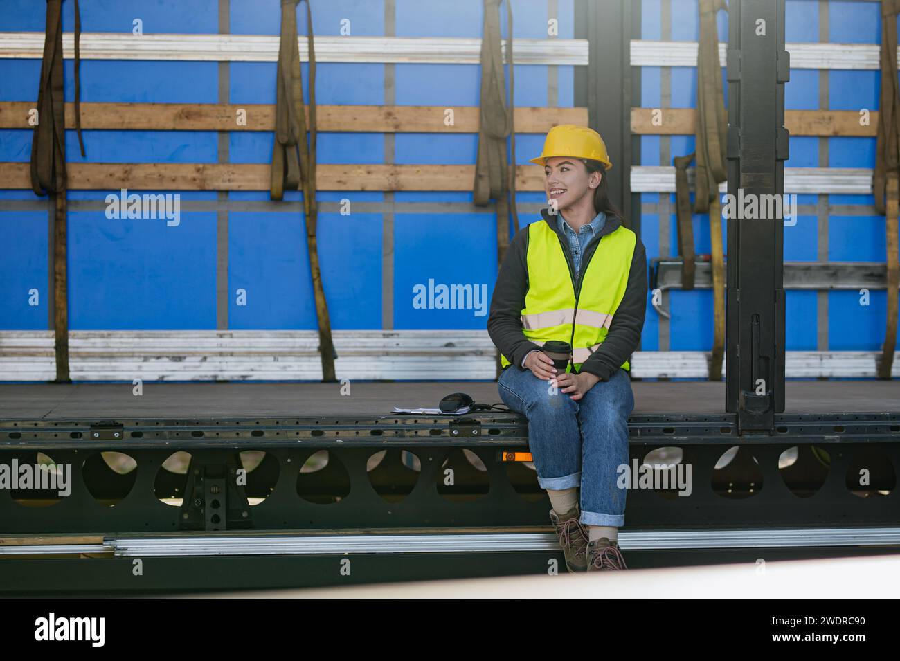 Weiblicher Lagerempfänger in reflektierender Weste und Helm im Laderaum, Anhänger. Stockfoto