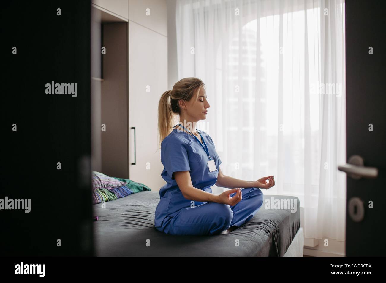Krankenschwester oder Ärztin genießt nach der Arbeit Freizeit zu Hause, Meditation. Work-Life-Balance für eine Pflegekraft. Stockfoto