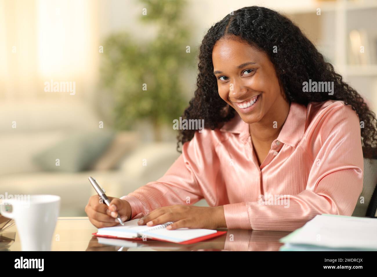 Ein schwarzer Freelancer, der in die Agenda schreibt, sieht dich zu Hause an Stockfoto