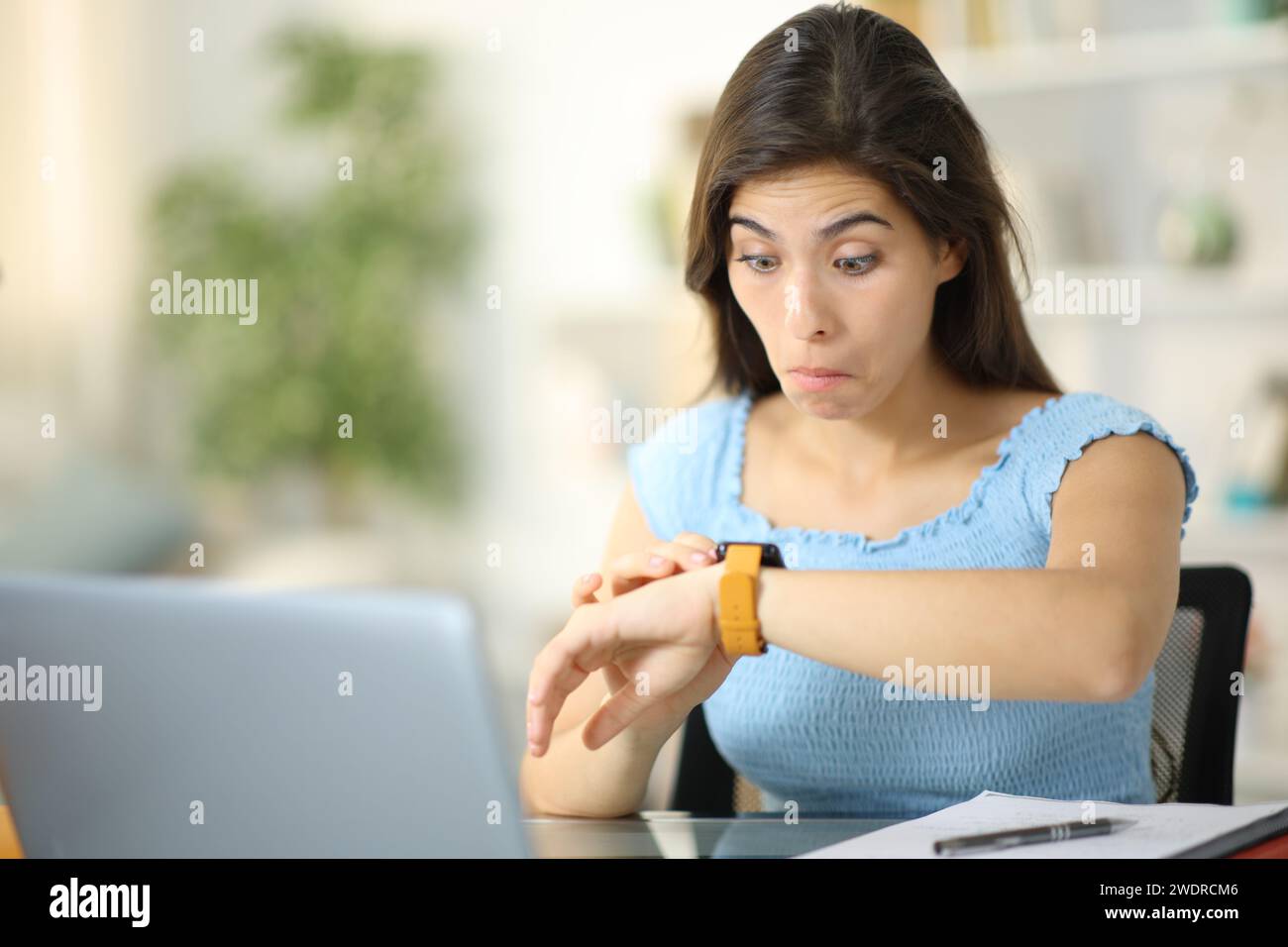 Verwirrter Schüler, der zu Hause Smartwatch-Inhalte überprüft Stockfoto