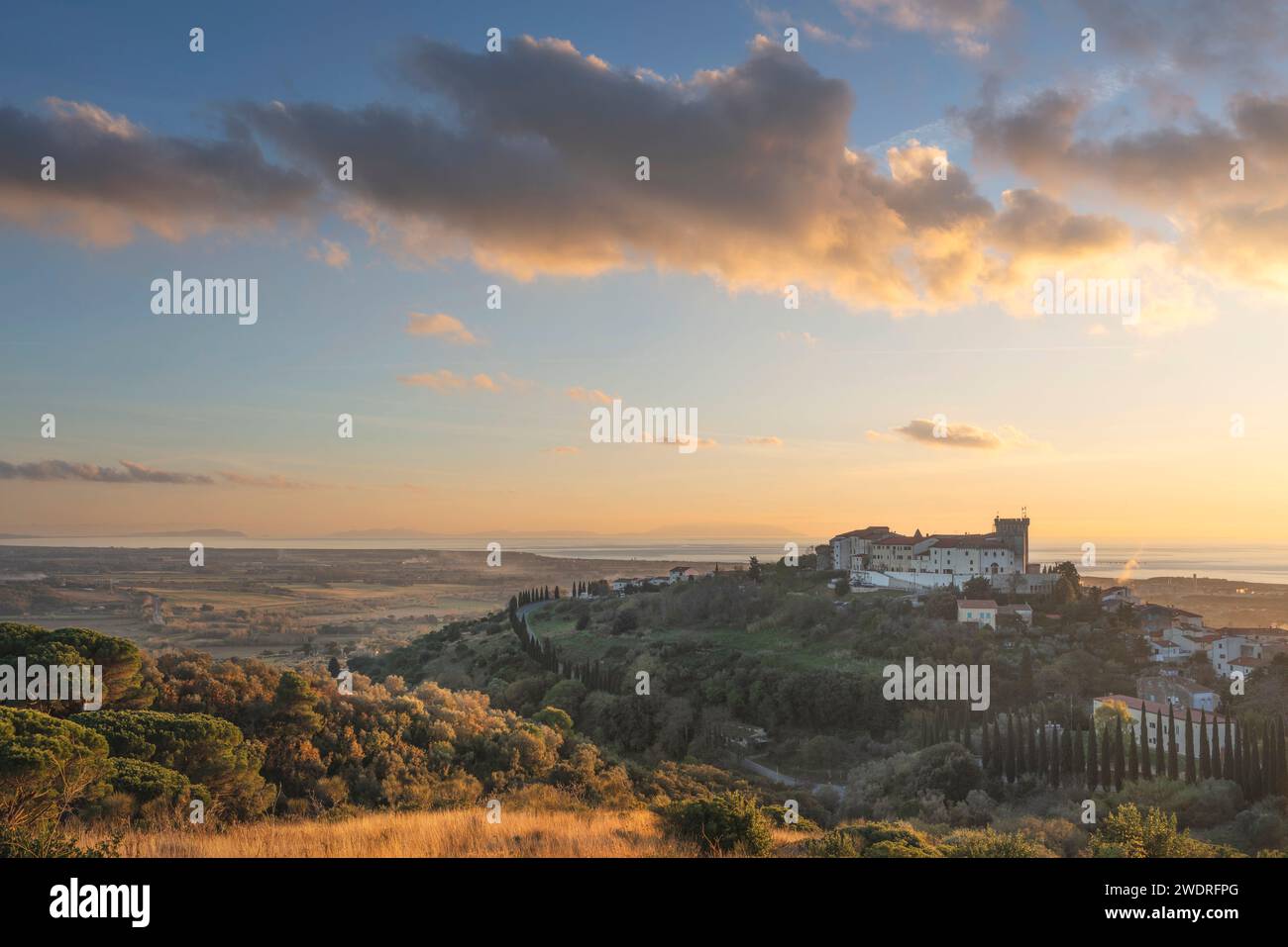 Blick von oben auf die Stadt Rosignano Marittimo und die Burg. Meer im Hintergrund bei Sonnenuntergang. Toskana, Italien Stockfoto