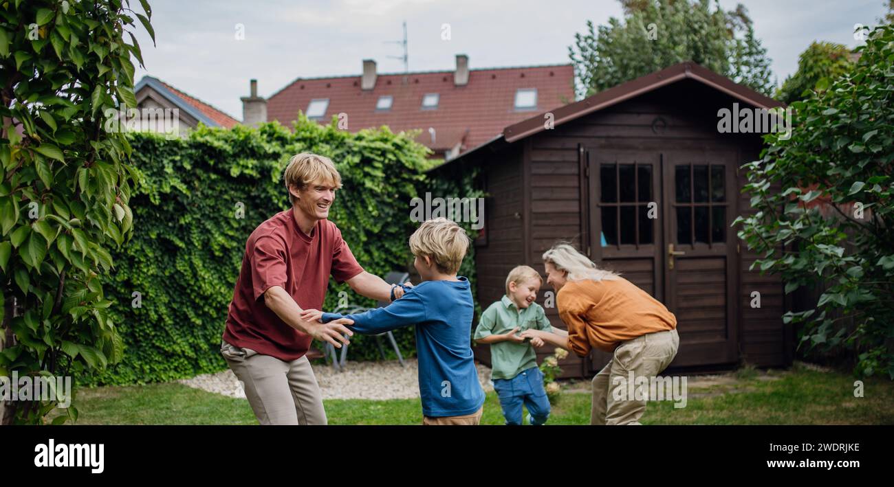 Eltern, die Spaß mit Söhnen im Garten haben, Bindungsmoment. Das Konzept der Kernfamilie. Stockfoto