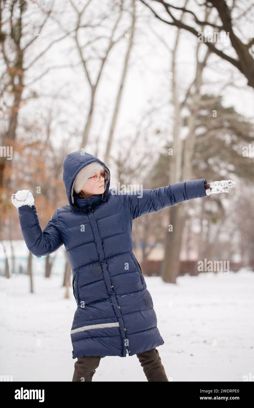 Das Mädchen wirft einen Schneeball Stockfoto