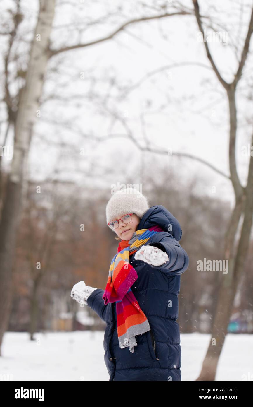 Ein Mädchen spielt mit Schneebällen in einem Winterpark Stockfoto