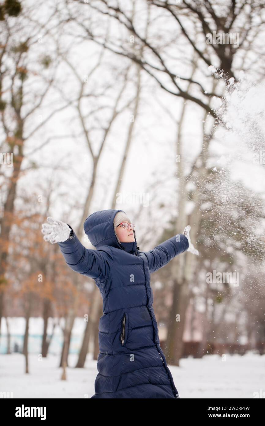 Das Teenager-Mädchen wirft Schnee auf Stockfoto