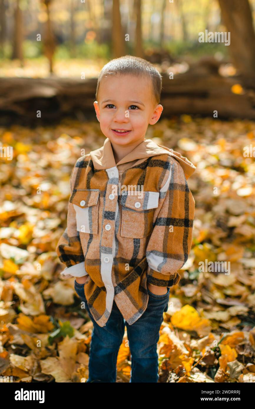 Porträt eines jungen glücklichen Kindes mit Händen in Taschen im Herbstlaub Stockfoto