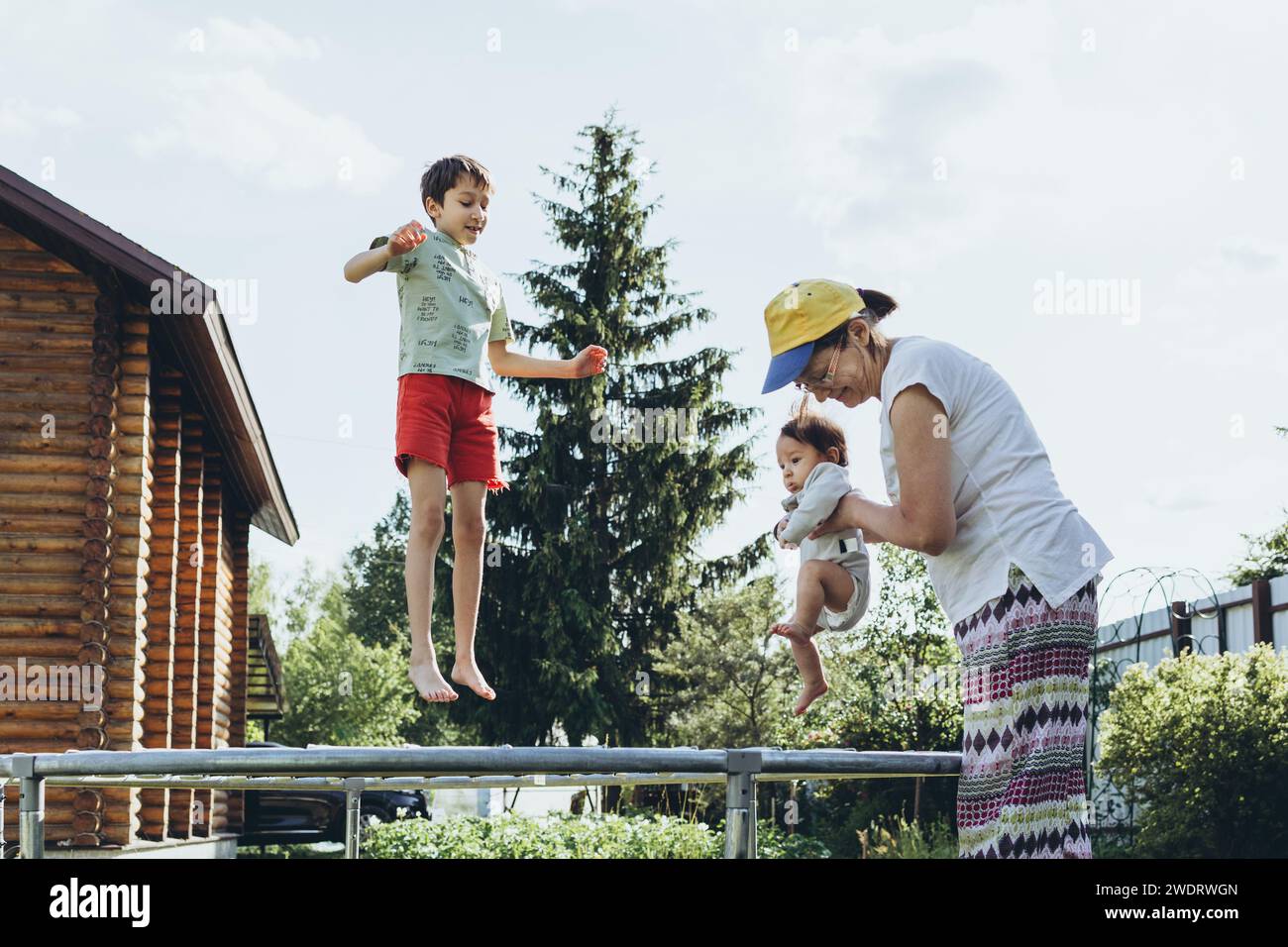 Oma mit Enkeln, die auf einem Trampolin im Hof springen Stockfoto