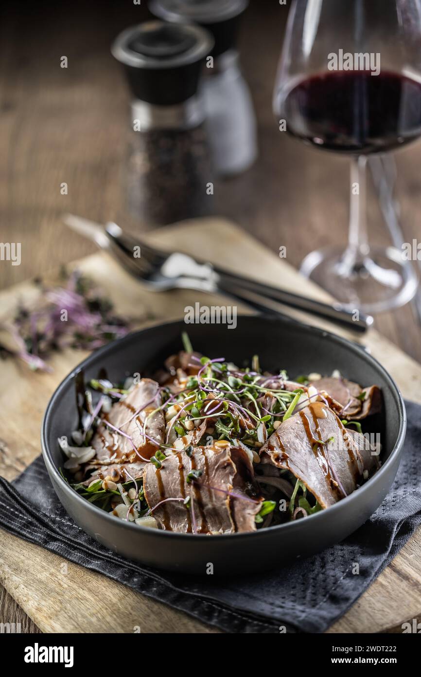 Roastbeef Salat mit Kräutern und Balsamico Soße im Stil einer Schüssel auf einem Restauranttisch. Stockfoto