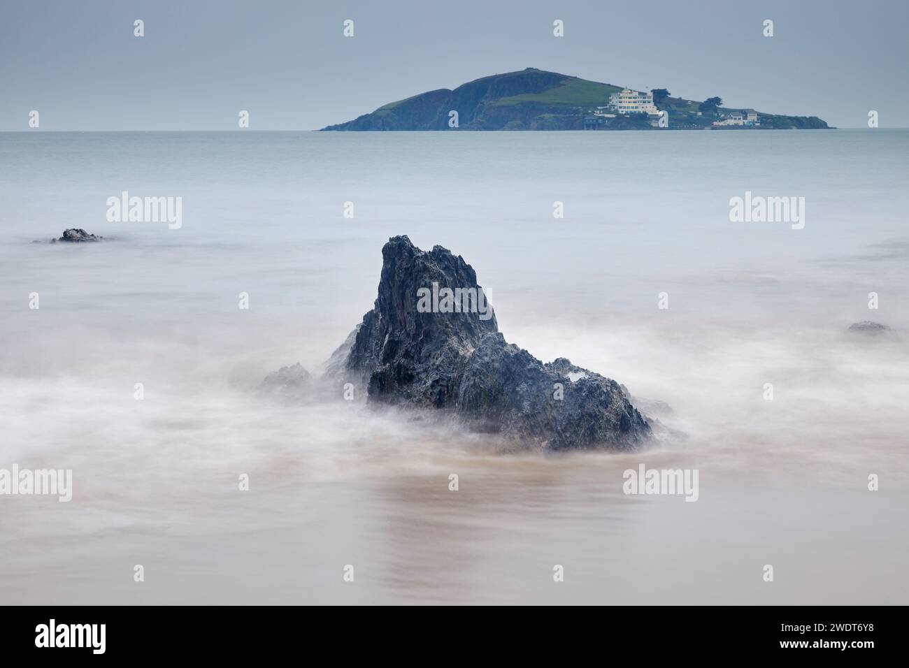 Ein Blick auf die Felsen am Strand von Bantham in der Abenddämmerung, mit Blick auf Burgh Island und das Hotel an der Südküste von Devon, England Stockfoto