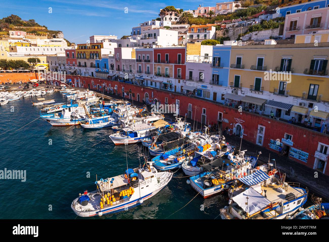 Aus der Vogelperspektive auf das farbenfrohe italienische Dorf Ponza mit Fischereifahrzeugen im Vordergrund, Pontinische Inseln Stockfoto