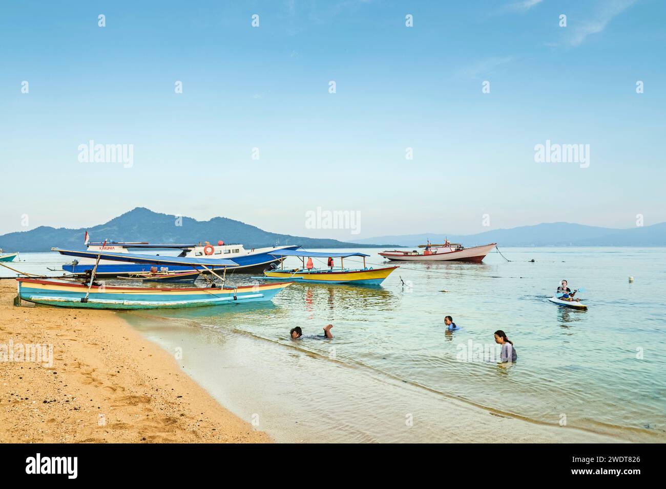 Einheimische schwimmen am Stadtstrand mit dem Festland dahinter auf dieser von Korallen gesäumten Urlaubsinsel Bunaken Island, Sulawesi, Indonesien, Südostasien, Asien Stockfoto