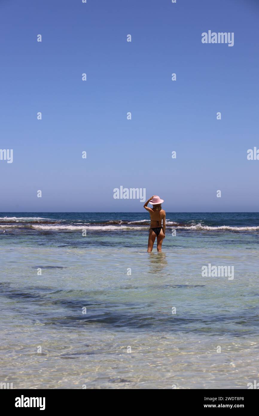 Eine junge Frau, die in flachen Gewässern des Ozeans steht Stockfoto