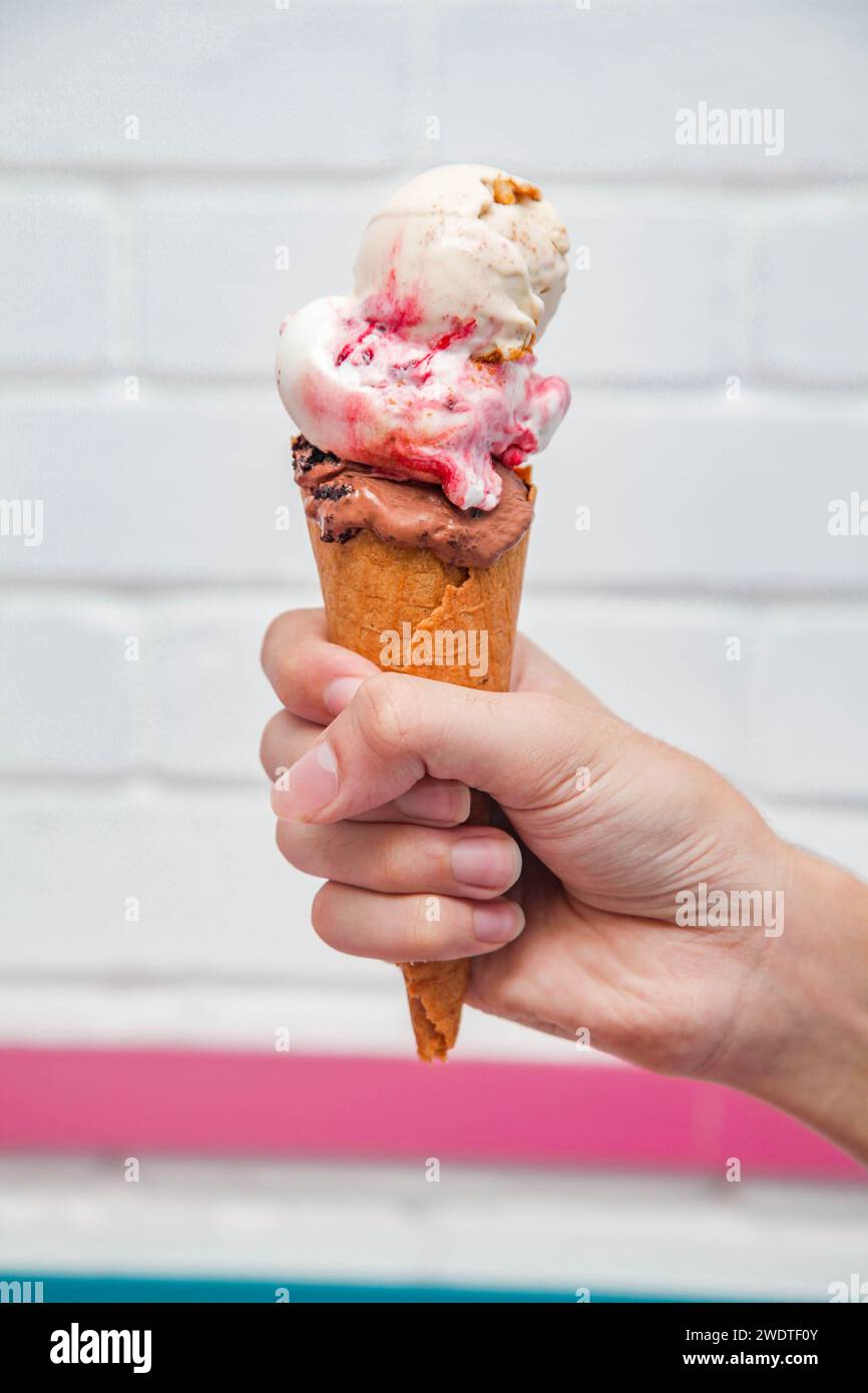 Eis Waffelkegel Eiscreme in der Hand mit weißem gemauertem Hintergrund. Stockfoto