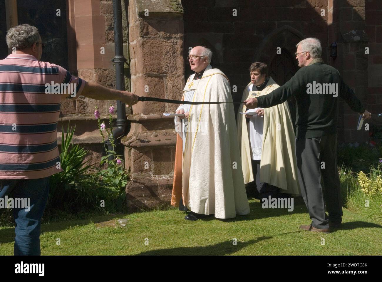 Pfarrer Edward Ward leitet die Gemeinde um die Kirche in der Clypping Ceremony St Peters Church, Edgmond, Shropshire UK 2015. Die Gemeinde hält die Hände in einem Kreis um die ganze Kirche, wenn sie können, taten sie es nur mit Gürteln und Seilen, um den ungebrochenen Kreis zu vervollständigen. England 2010er Jahre HOMER SYKES Stockfoto