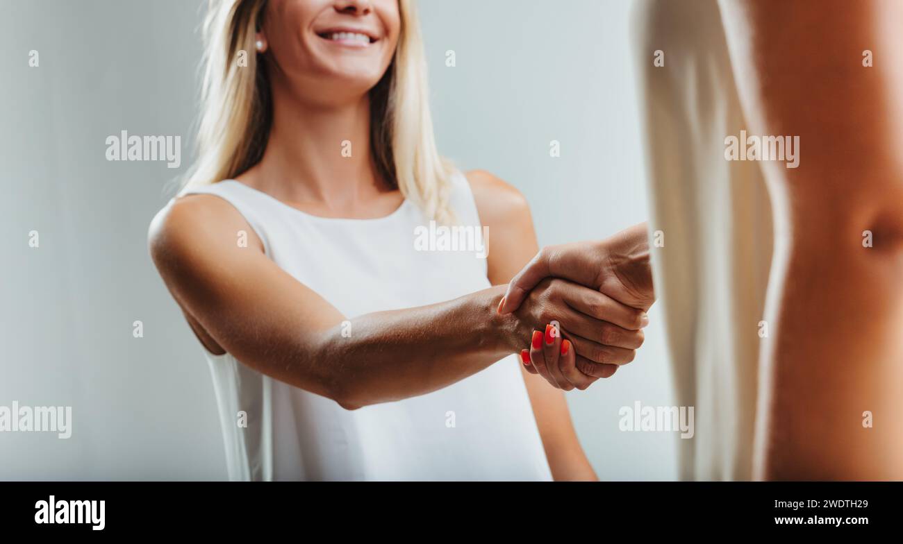 Die Frau betätigt sich in einem festen Handschlag, ihr Blick deutet auf Selbstvertrauen und professionelle Absichten hin Stockfoto