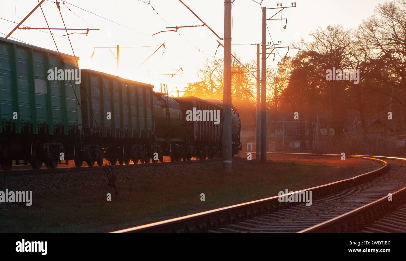 Wunderschöner, fabelhafter Sonnenuntergang mit den Sonnenstrahlen, die einen vorbeifahrenden Güterzug erleuchten. Stockfoto