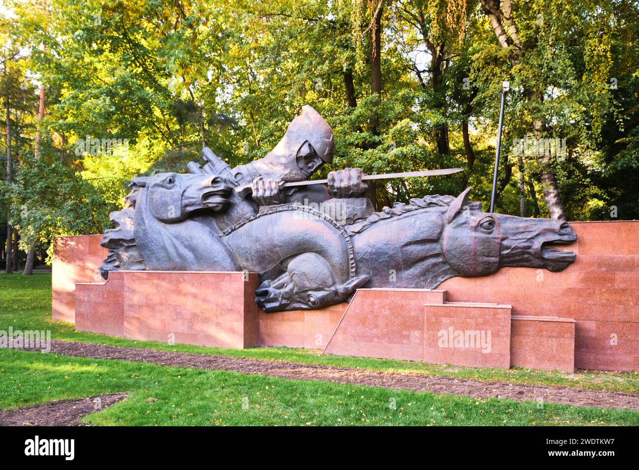 Links befindet sich der Teil der Gedenkstätte mit einem „Eid“-Thema, ein Soldat führt Pferde. Am Denkmal des Ruhms im Panfilov Park in Almaty, Kasachstan. Stockfoto
