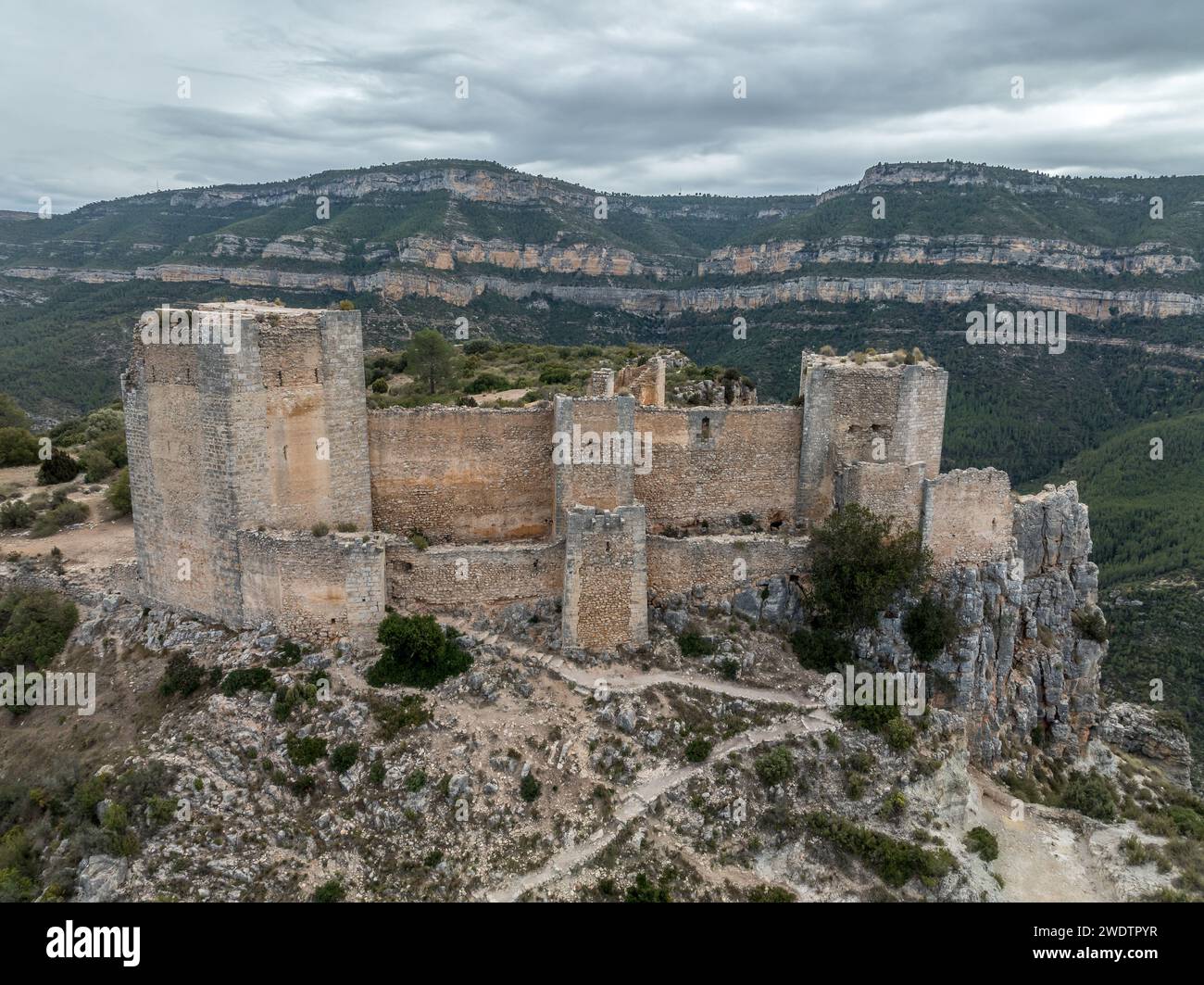 Panoramablick auf das Schloss Chirel auf einem felsigen Felsen, der über die El Jugar-Schlucht in Cortes de Pallas ragt, mit dreieckigem Grundriss und Pfeilschlitzen Stockfoto