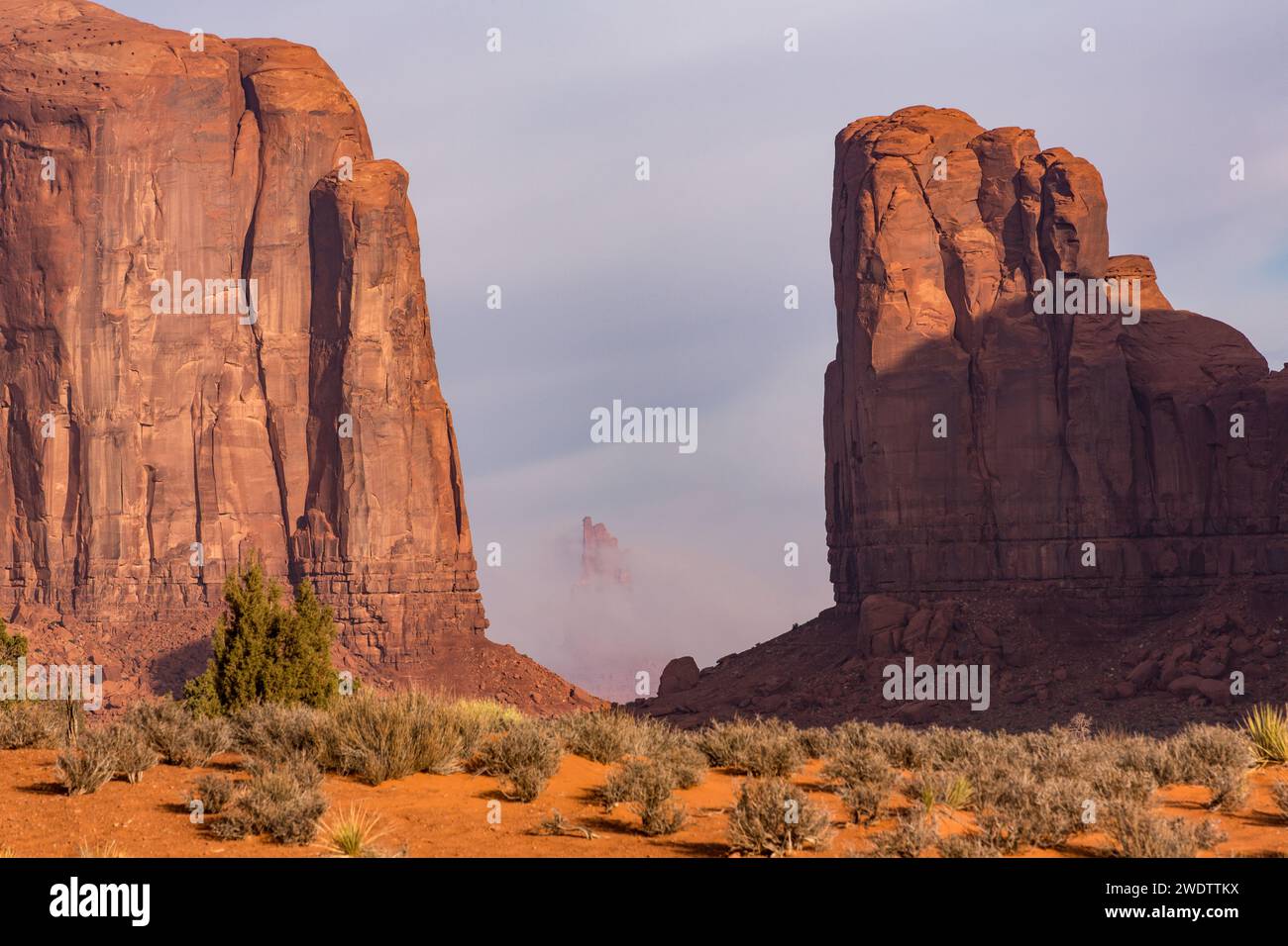 Foggy Morning North-Fenster mit Blick auf den großen Indianerhäuptling, eingerahmt von Elephant Butte & Cly Butte im Monument Valley Navajo Tribal Park in Arizona. Stockfoto