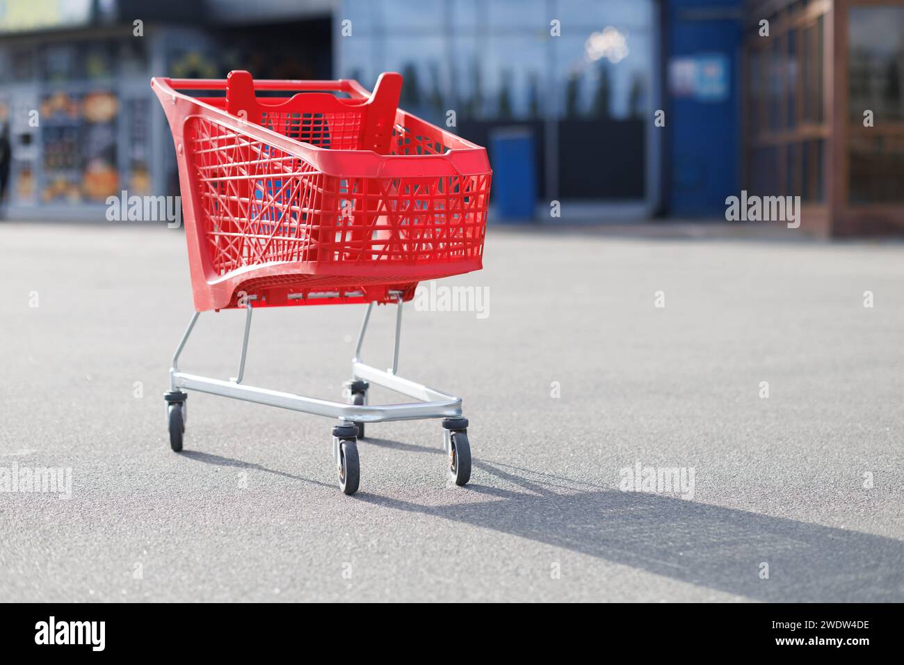 Ein roter Supermarktkorb auf dem Parkplatz. Hochwertige Fotos Stockfoto