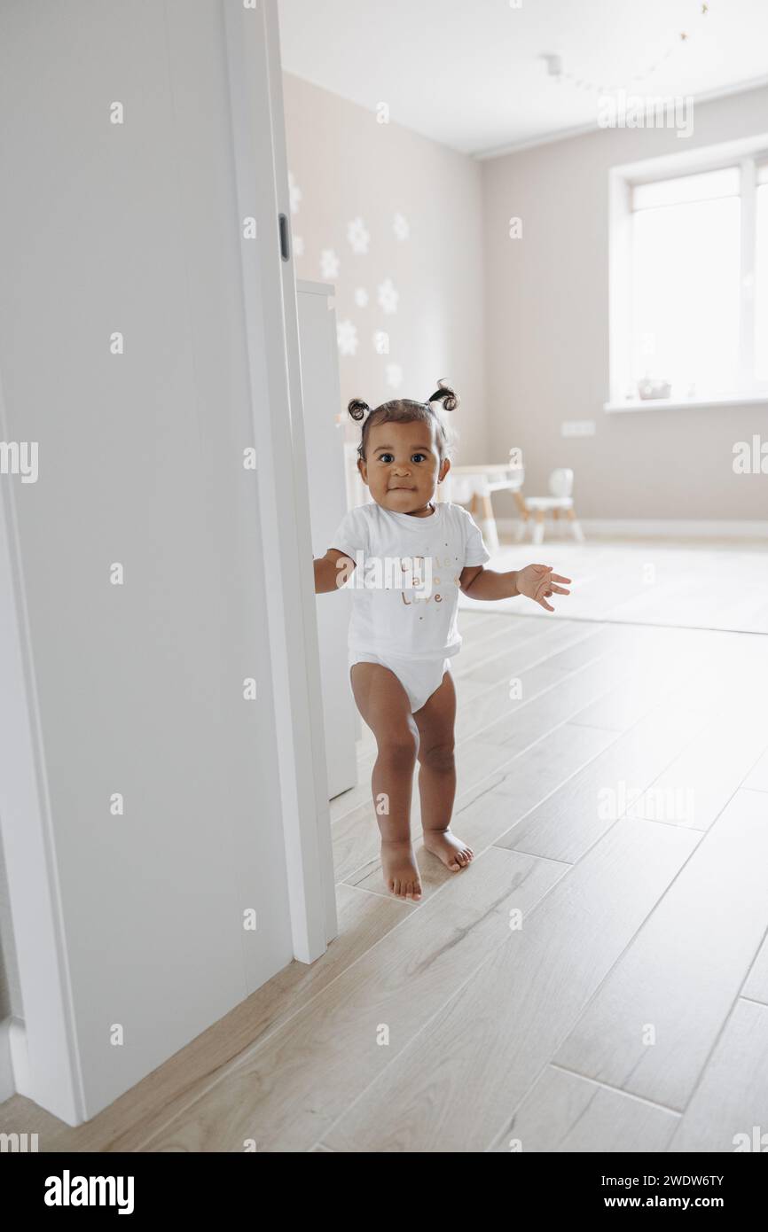 Gemischtes Kleinkind, das im Zimmer läuft. Afrokaukasisches kleines Mädchen. Das Konzept der interrassischen Familie. Stockfoto