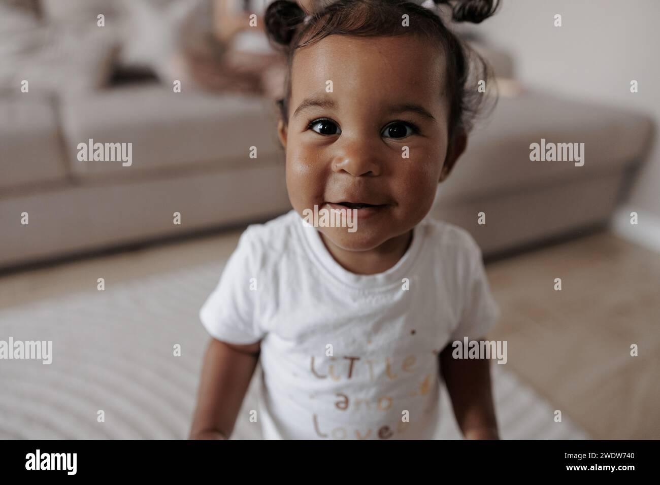 Porträt eines fröhlichen, gemischten Kleinkindes im Zimmer. Afrokaukasisches kleines Mädchen. Das Konzept der interrassischen Familie. Stockfoto