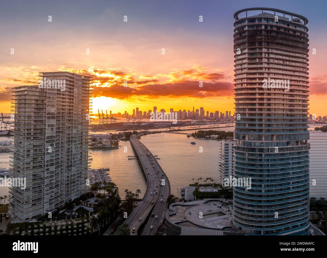 Blick aus der Luft auf die Skyline von Miami mit dramatischem farbenfrohem Sonnenuntergangshimmel, MacArthur Causeway zwischen zwei neuen Immobilienentwicklungen Luxus-Ferienwohnung Gebäude i Stockfoto