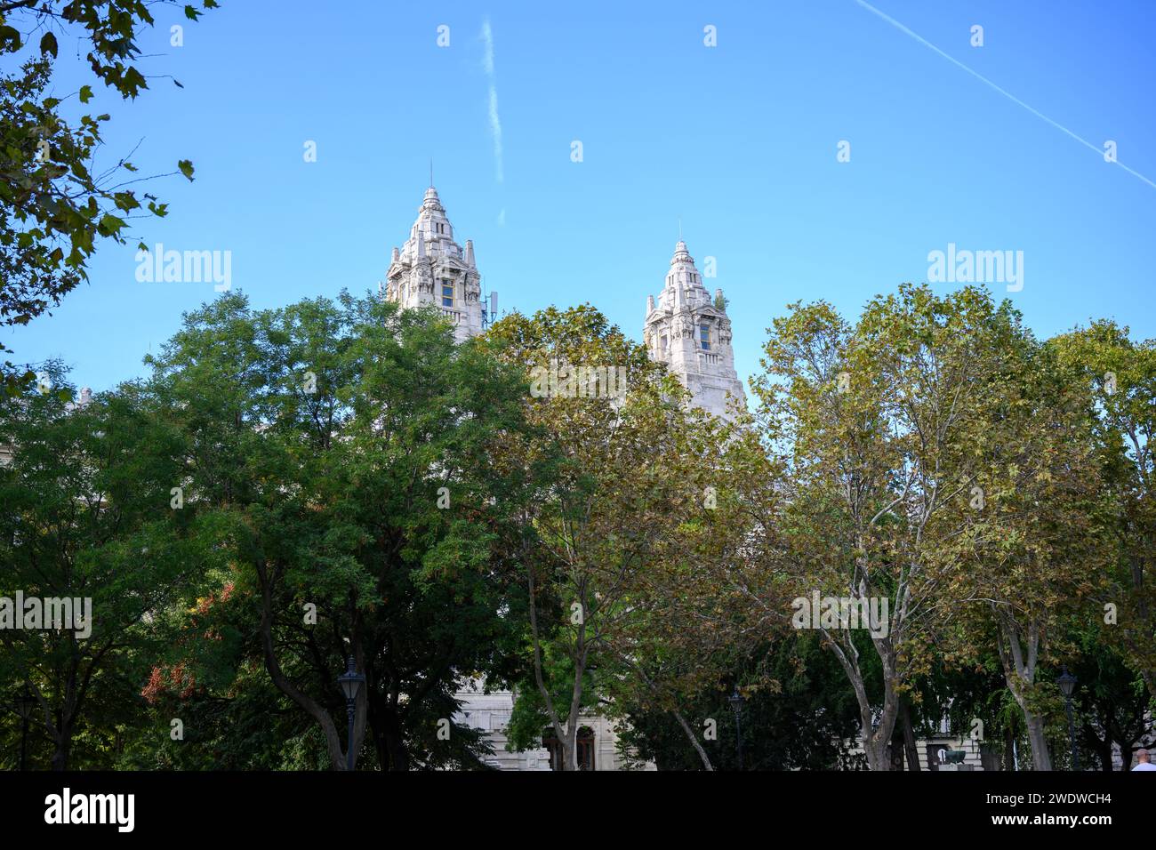 Die Kirchtürme eine Pfarrkirche auf der Szabadság Ter durch das Laub von Bäumen gesehen, Budapest, Ungarn Stockfoto