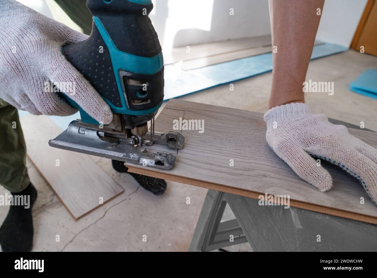 Man sägt Laminat. Der Mann repariert den Boden im Haus, Laminatboden im Stil alter Bretter. Stockfoto