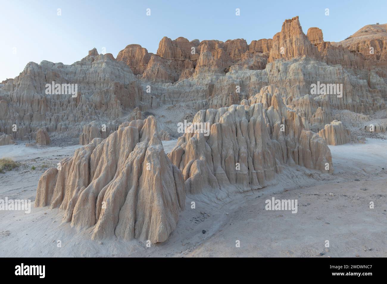 Kleine Felsformation steht vor der großen roten und gelben Felswände im Cathedral Gorge State Park. Stockfoto