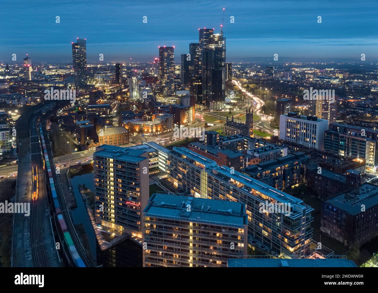 Luftaufnahme in der Abenddämmerung zur Hauptverkehrszeit eines Güterzugs nach Manchester mit Mancunian Way, Castlefield und New Jackson mit dem Stadtzentrum dahinter Stockfoto