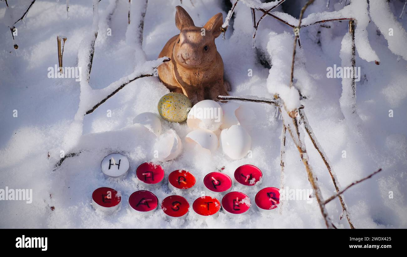 Frohe Ostern steht auf roten Teelichtern, die im Schnee liegen. Stockfoto