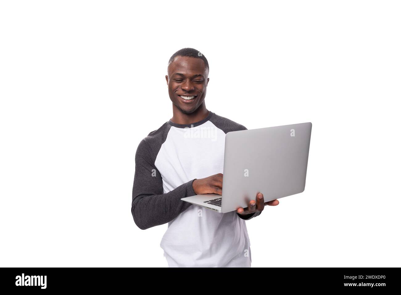 Junger amerikanischer Mann, der sich lässig mit einem Laptop bekleidet hat Stockfoto