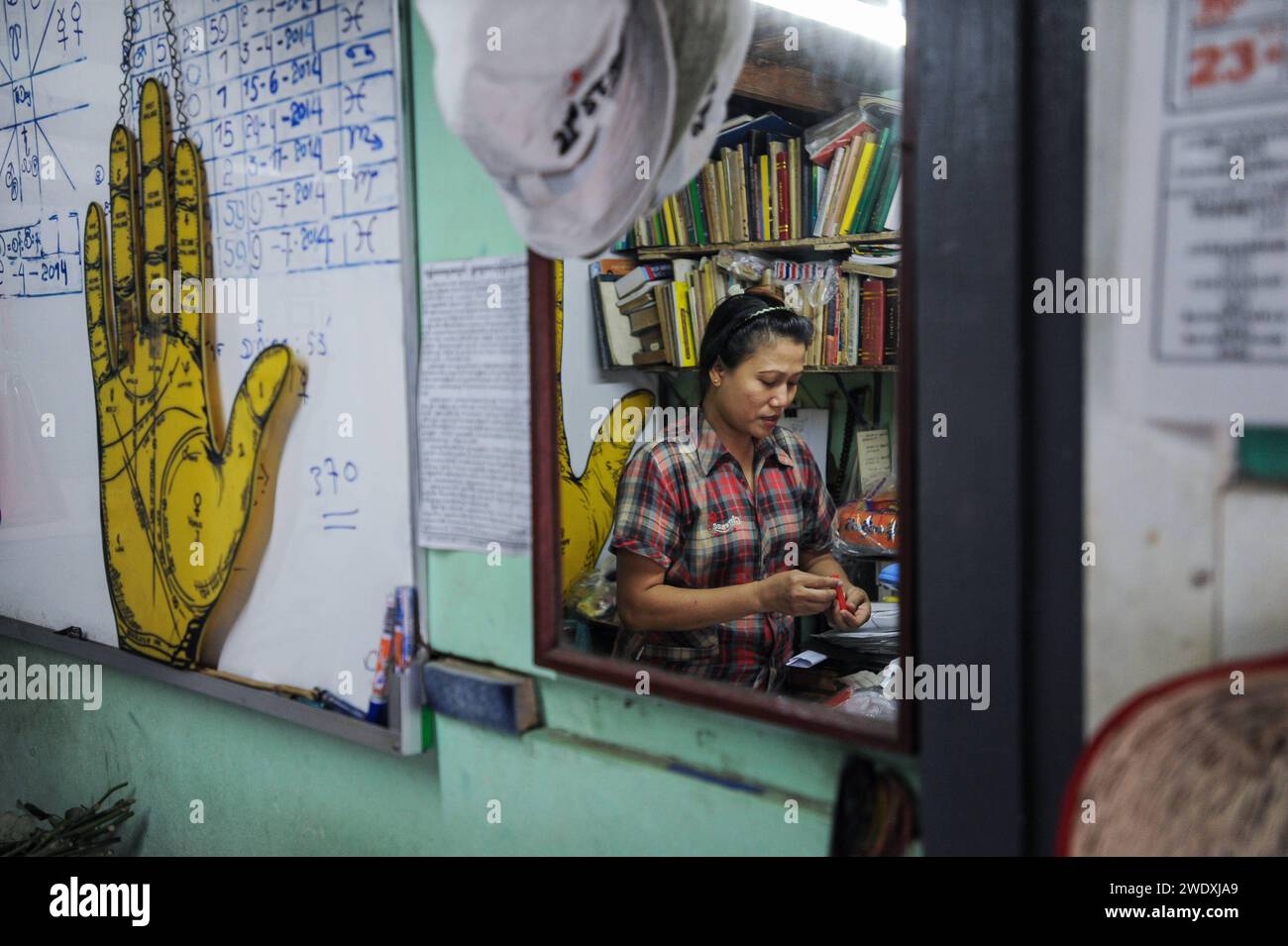 01.04.2014, Yangon, Myanmar, Asien - eine Handleserin und Wahrsagerin spiegelt sich in einem Spiegel in ihrem kleinen Orakel-Studio. *** 01 04 2014, Yangon, Myanmar, Asien Ein Handleser und Wahrsagerin spiegelt sich in einem Spiegel in ihrem kleinen oracle-Studio Stockfoto