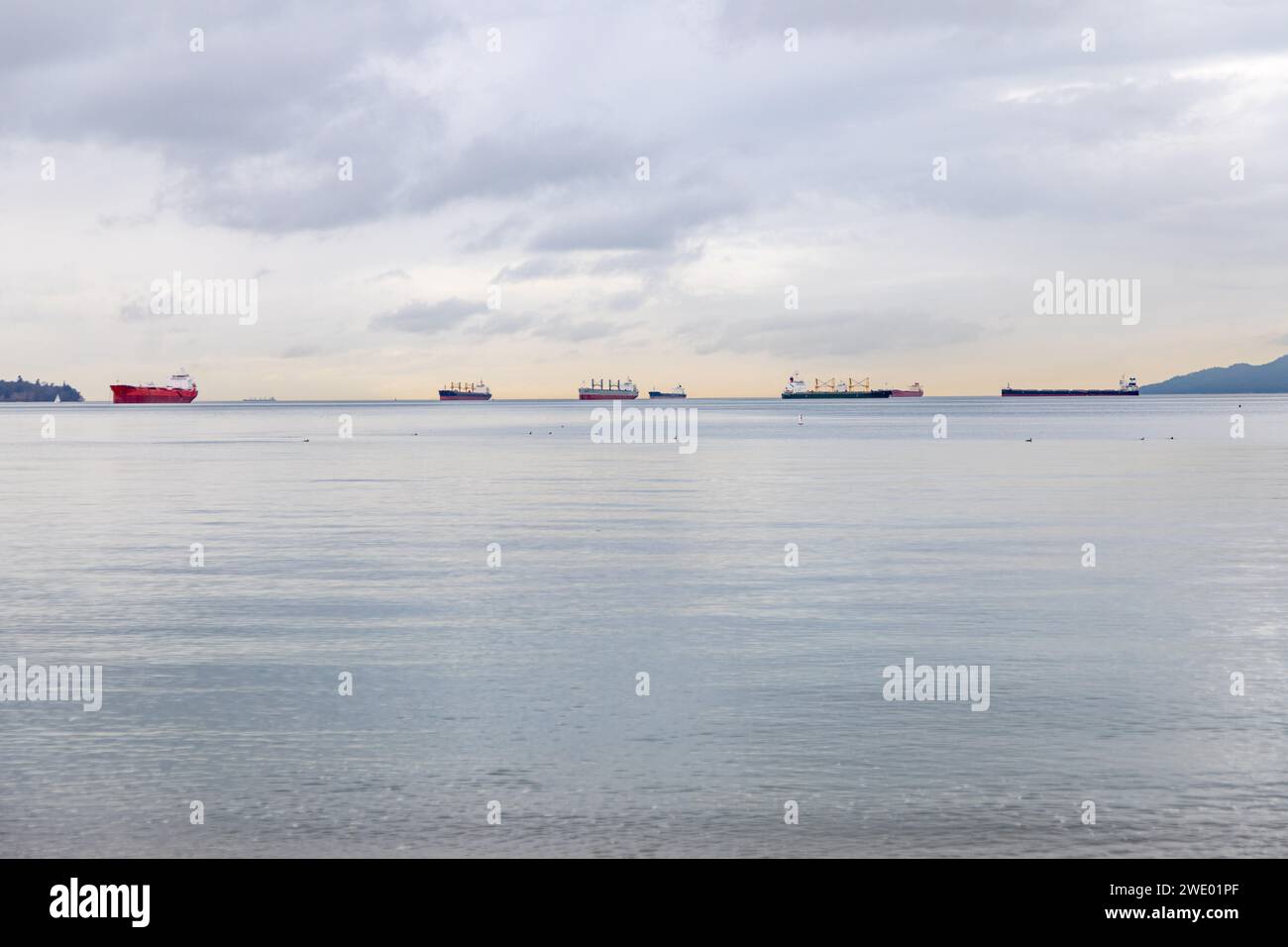 Container- und Frachtschiffe, die in den Gewässern des Burrard Innlet sitzen und von English Bay, Vancouver, British Columbia BC, gesehen werden Stockfoto
