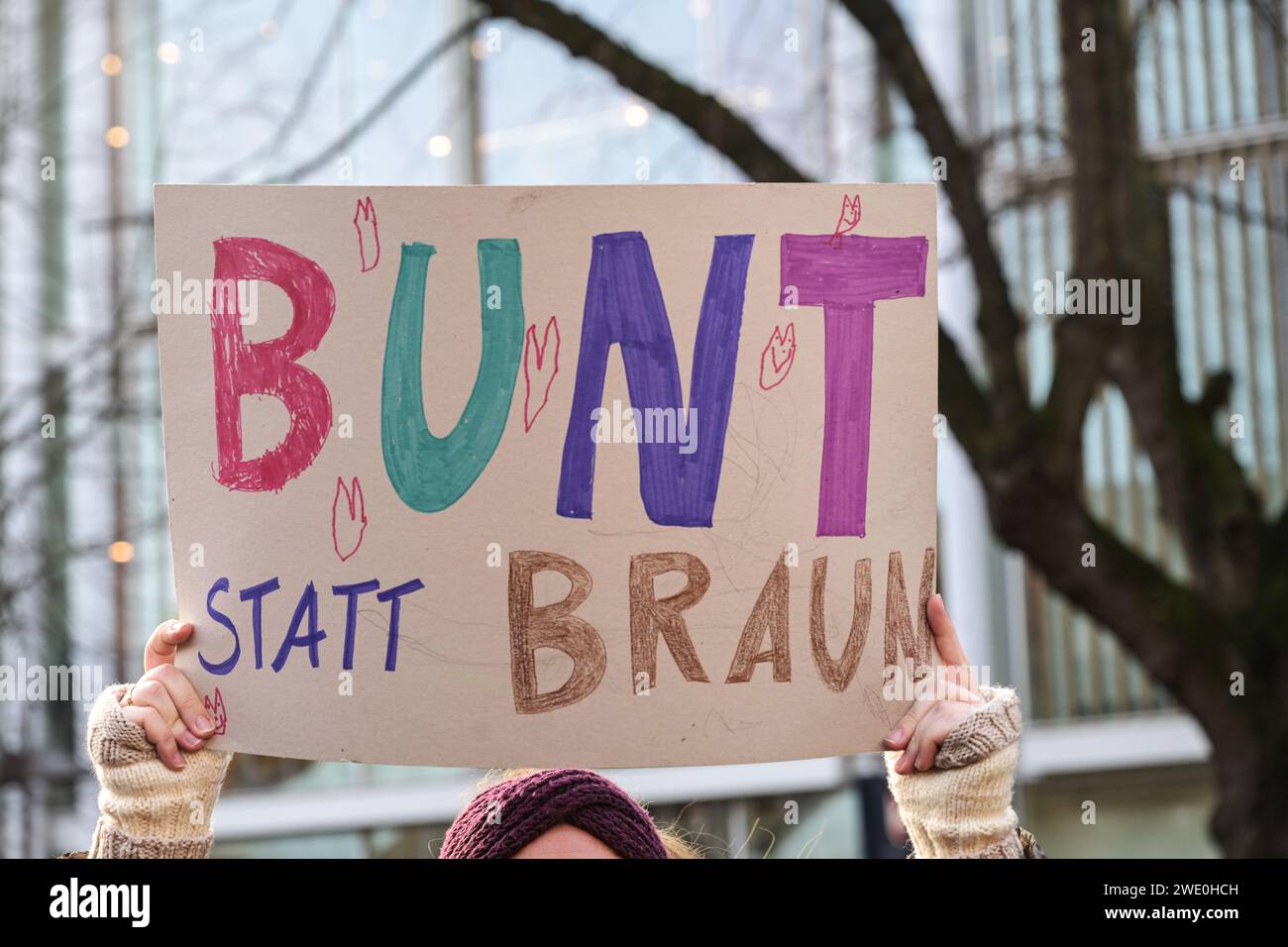 Frau, die ein Pappschild mit dem deutschen Text Bunt statt Braun hält, als Protest gegen Rassismus und neonazistischen Faschismus auf einem Stockfoto